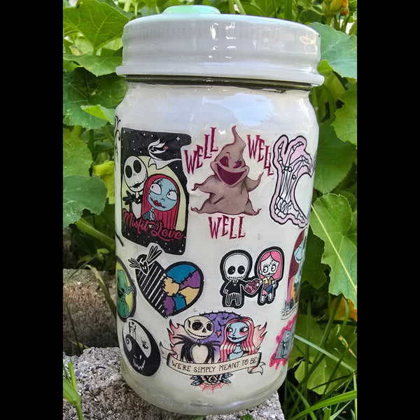 A white ceramic jar with a lid, decorated with colorful cartoon characters and text, lying on a concrete ledge outdoors with green leaves in the background.